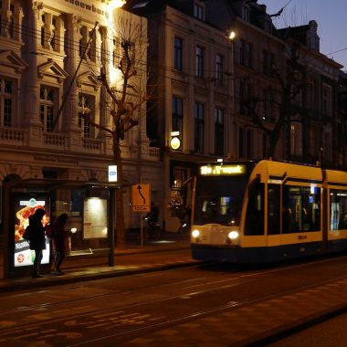 people walking on sidewalk near white and yellow tram during daytime