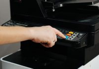 A person is pressing a button on a printer