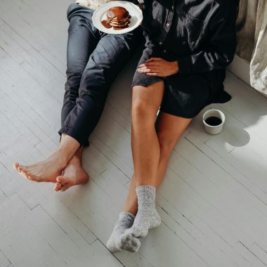 A cozy couple enjoying a quiet breakfast with pancakes and coffee on a sunlit floor.