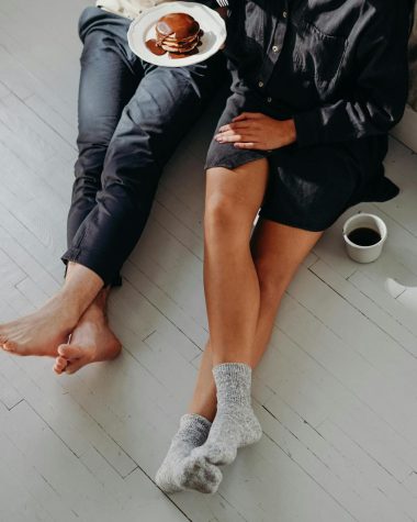 A cozy couple enjoying a quiet breakfast with pancakes and coffee on a sunlit floor.
