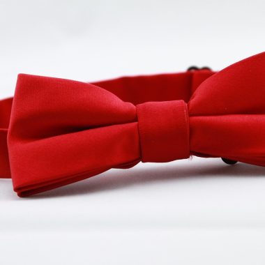 Verschillende rode kledingstukken en accessoires naast elkaar, waaronder een rode blouse, tas en sjaal in uiteenlopende tinten rood