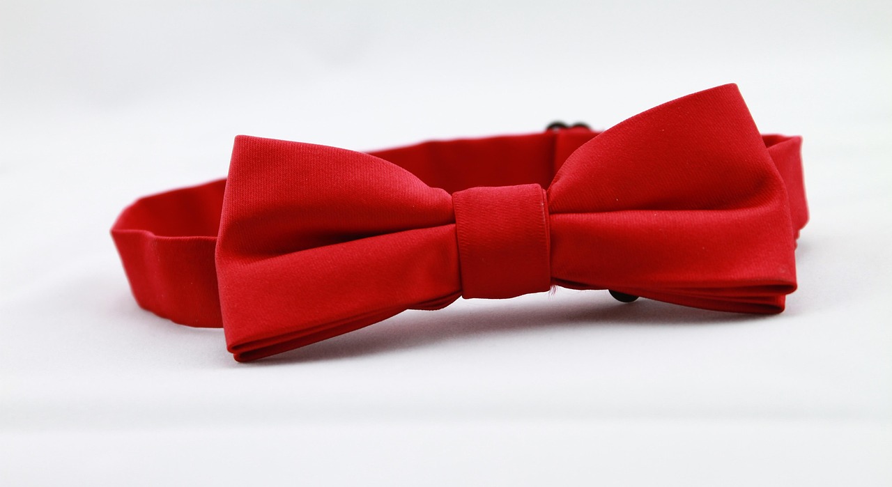 Verschillende rode kledingstukken en accessoires naast elkaar, waaronder een rode blouse, tas en sjaal in uiteenlopende tinten rood
