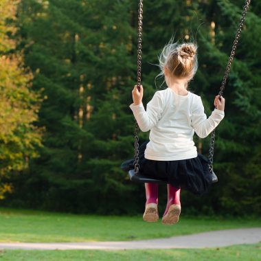Peuter in laagjesoutfit speelt buiten in de herfst tussen gevallen bladeren