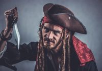 Piraten accessoires voor kinderen zoals een ooglapje, hoofddoek en zwaard uitgestald op een houten tafel