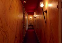 Smalle gang met wandarmaturen die zachte verlichting geven langs de muren